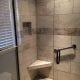 Beautiful tiled walk-in shower with built-in bench, glass door, modern fixtures, and decorative tile accents, showcasing professional bathroom remodeling by My Contracting Guy.