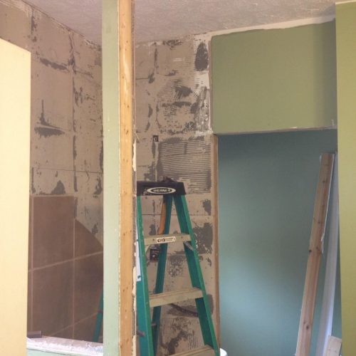New bathroom remodeling under construction with drywall installation and green painted walls. Skilled contractor work for bathroom upgrades and renovation projects.