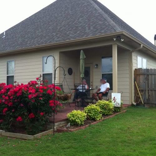 Vibrant backyard patio with lush garden, seating area, and well-maintained lawn, showcasing professional home exterior and deck installation services by My Contracting Guy.
