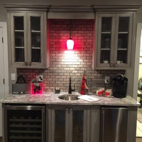 Stylish home bar area with cabinetry, granite countertop, wine cooler, and festive holiday decorations for a cozy Christmas gathering.