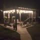 String lights illuminating a backyard patio with seating, a swing, and a playset; perfect for outdoor entertainment and backyard remodeling projects.