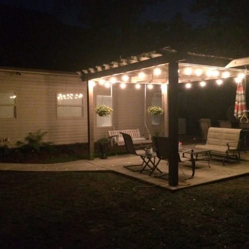 String lights illuminating a cozy outdoor patio with furniture and a swing, perfect for backyard entertaining and relaxation.
