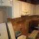New kitchen renovation with cabinetry installation in progress, showcasing white cabinets, construction tools, and renovation materials.