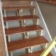 Newly installed wooden staircase steps with a dark stain finish, supported by light-colored framing, in the process of renovation or construction.