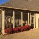 Enhanced outdoor backyard patio with screened-in porch and cozy seating area, perfect for relaxing and entertaining. Featuring durable window frames, lush landscaping, and a privacy fence for a comfortable outdoor living space.