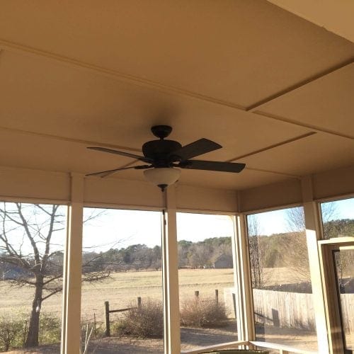 Bright enclosed porch with ceiling fan, large windows, scenic outdoor view, perfect for relaxing or entertaining. Skilled residential and commercial contracting services available for home renovations.