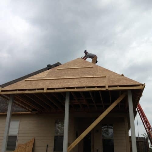 New roof installation on a house with a worker placing shingles, showcasing quality roofing services by My Contracting Guy.